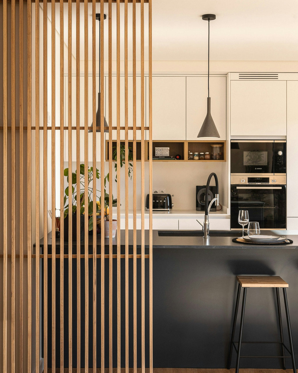 Silestone Charcoal Soapstone — îlot de cuisine noir mat derrière un claustra de chêne clair, armoires crème | Union Stone